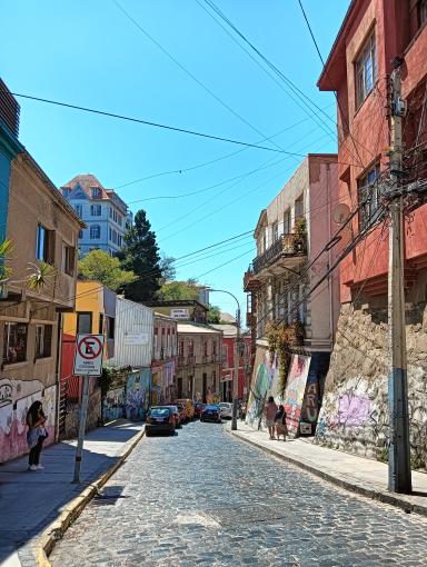 Calle patrimonial de Valparaíso con adoquines, fachadas coloridas y arte urbano